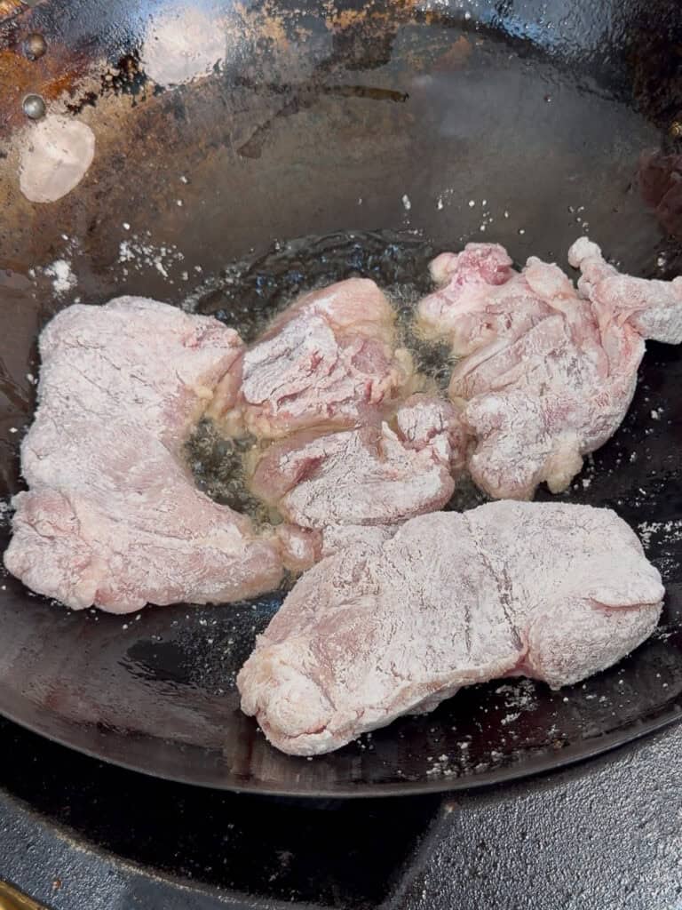 Chicken added to wok in a single layer