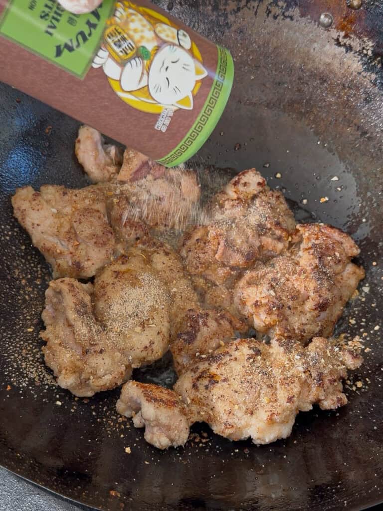 Seasoning sprinkled over chicken during slow sear