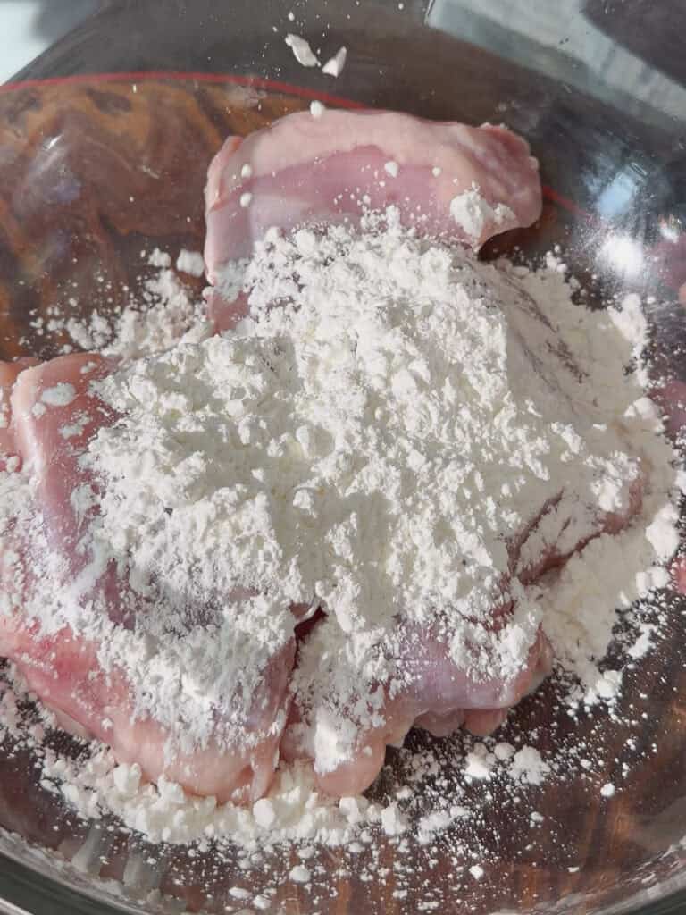 Chicken thighs arranged in a bowl before coating