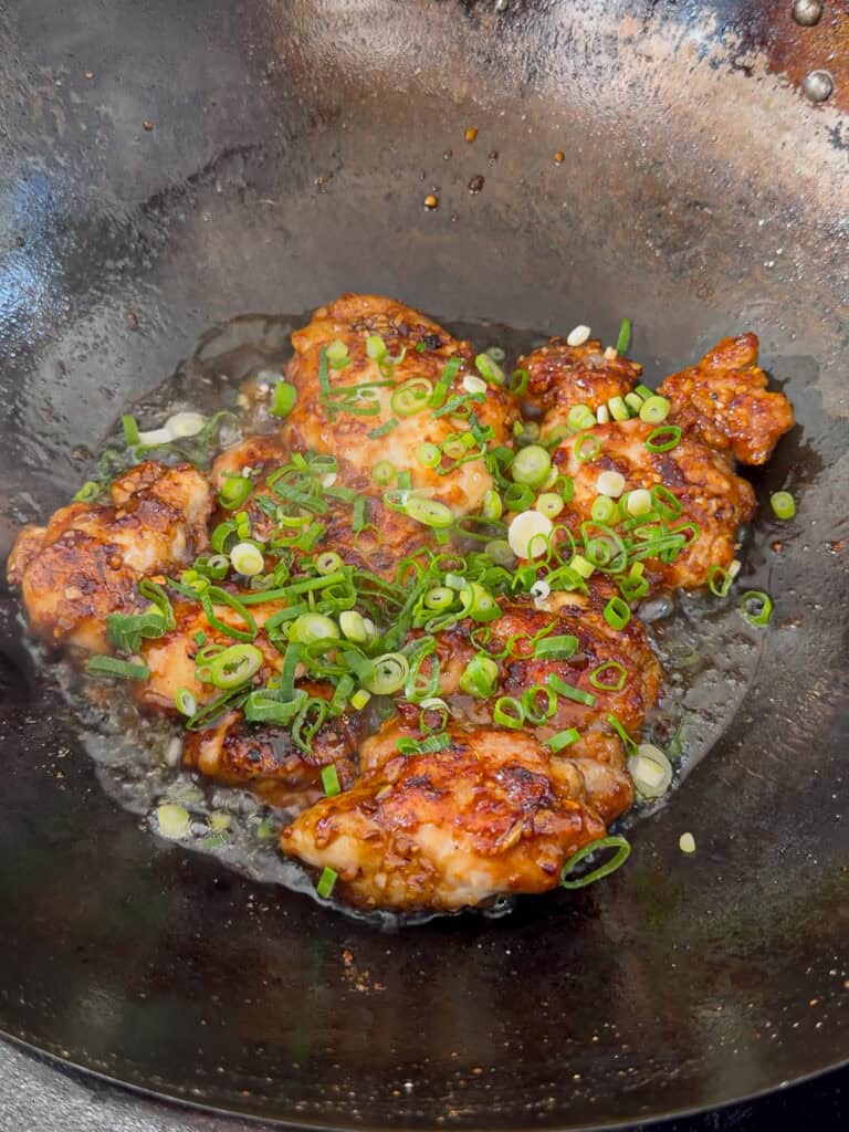 Chopped spring onions added to orange chicken