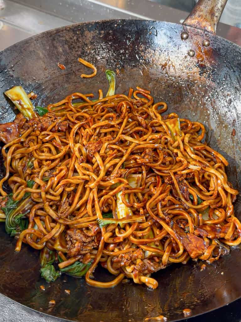Finished Shanghai pork noodles in a wok with bok choy and rich sauce