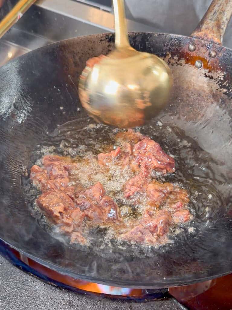 Raw beef cooking in bubbling oil.
