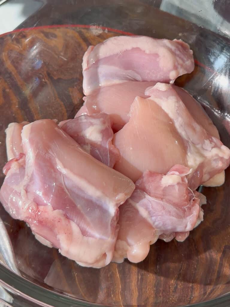 Raw chicken thigh pieces placed in a bowl for orange chicken