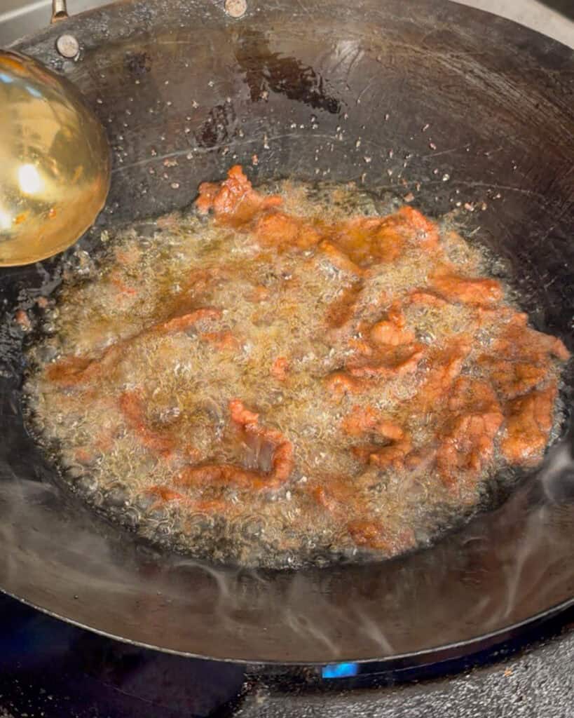 Beef pieces frying in hot oil in a wok