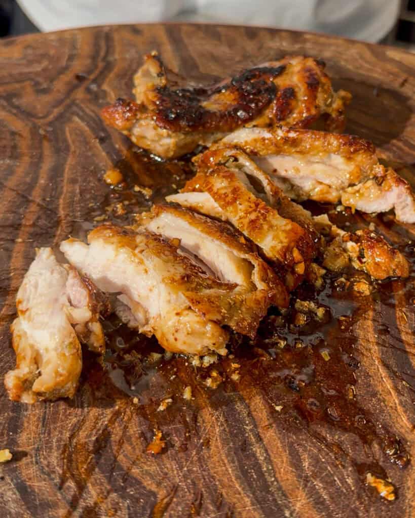 Cooked chicken pieces resting on a wooden cutting board