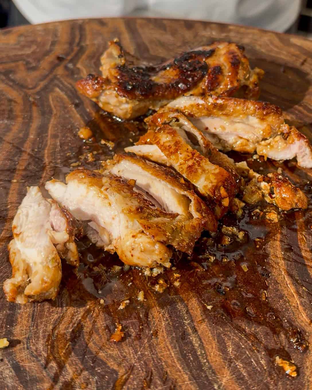 Cooked chicken pieces resting on a wooden cutting board