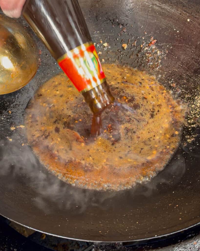 Dark sauce being poured into wok