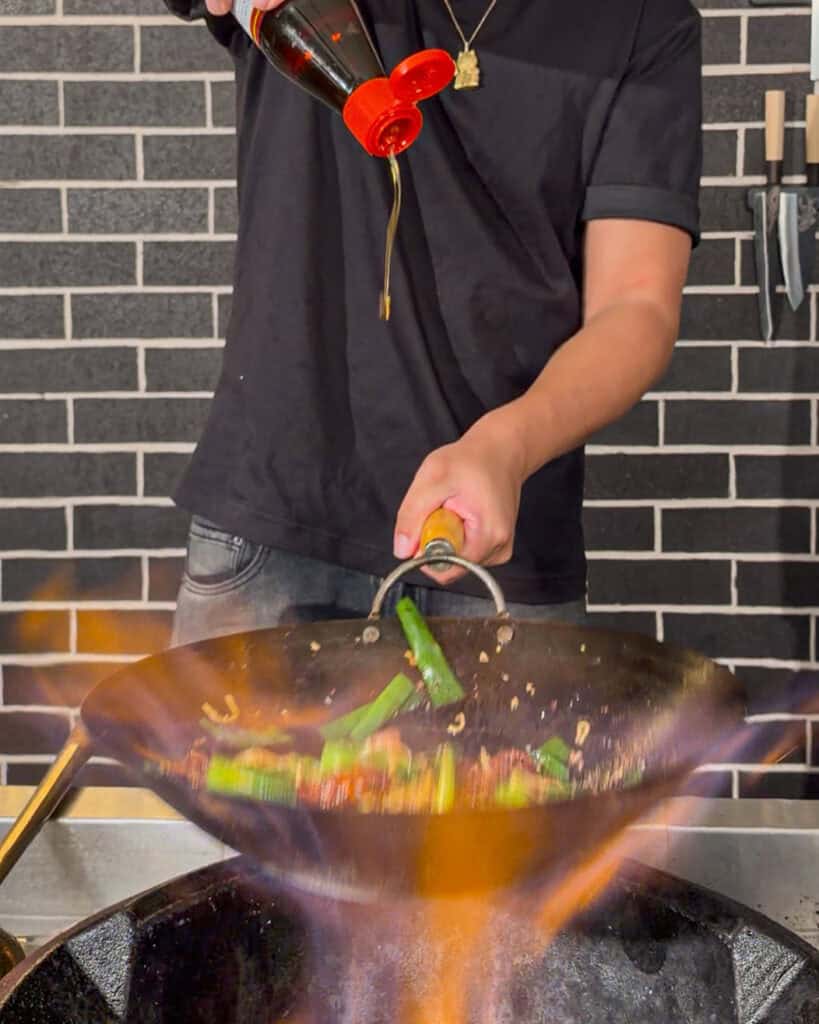 Liquid is visibly being poured into the wok