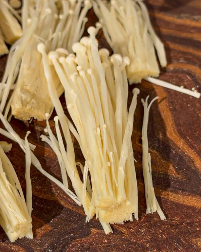 Separated enoki mushroom sections on wooden board