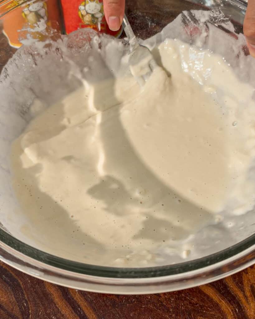 Shows a smooth light-colored mixture being stirred inside a bowl