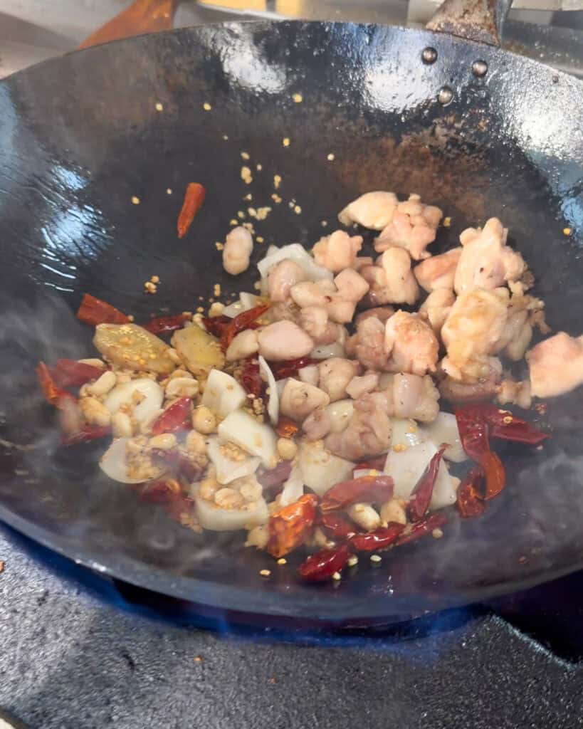 Chicken with dried red chillies peanuts onion and aromatics in a wok
