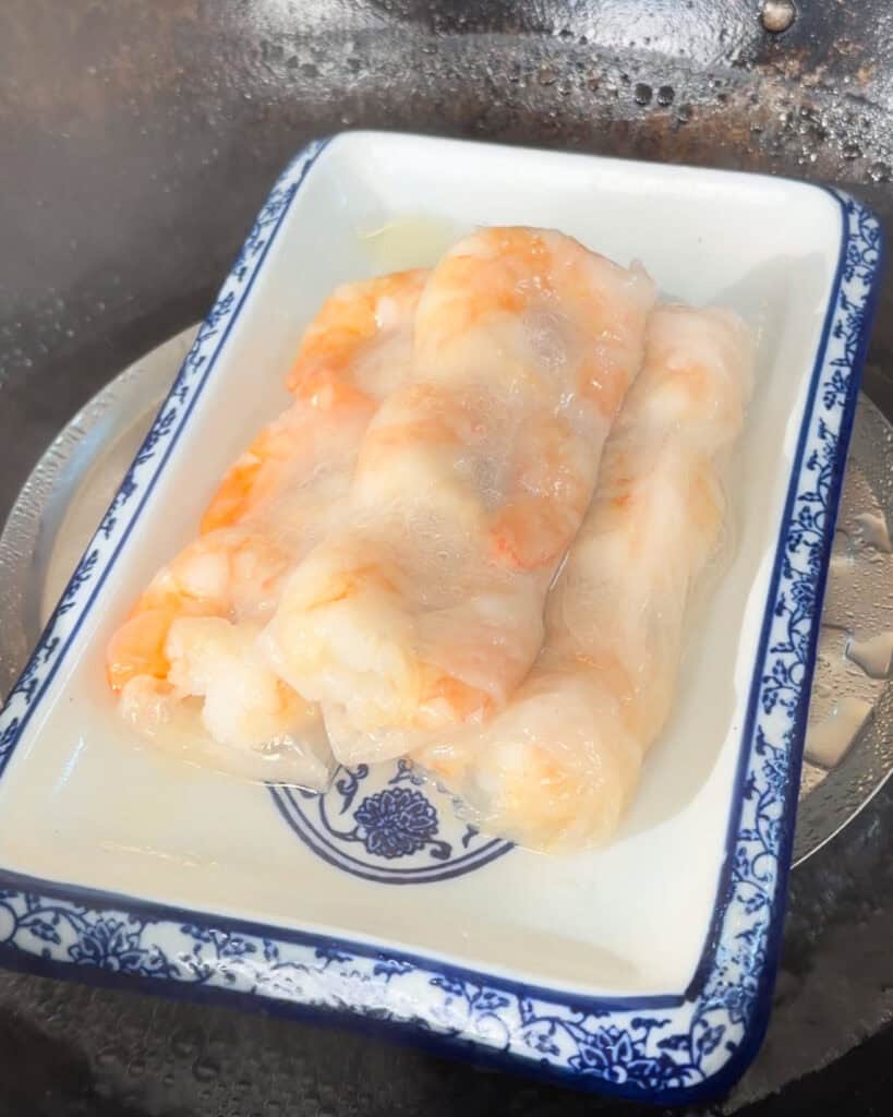 Raw shrimp peeled and arranged in a blue-and-white ceramic dish on a stainless surface