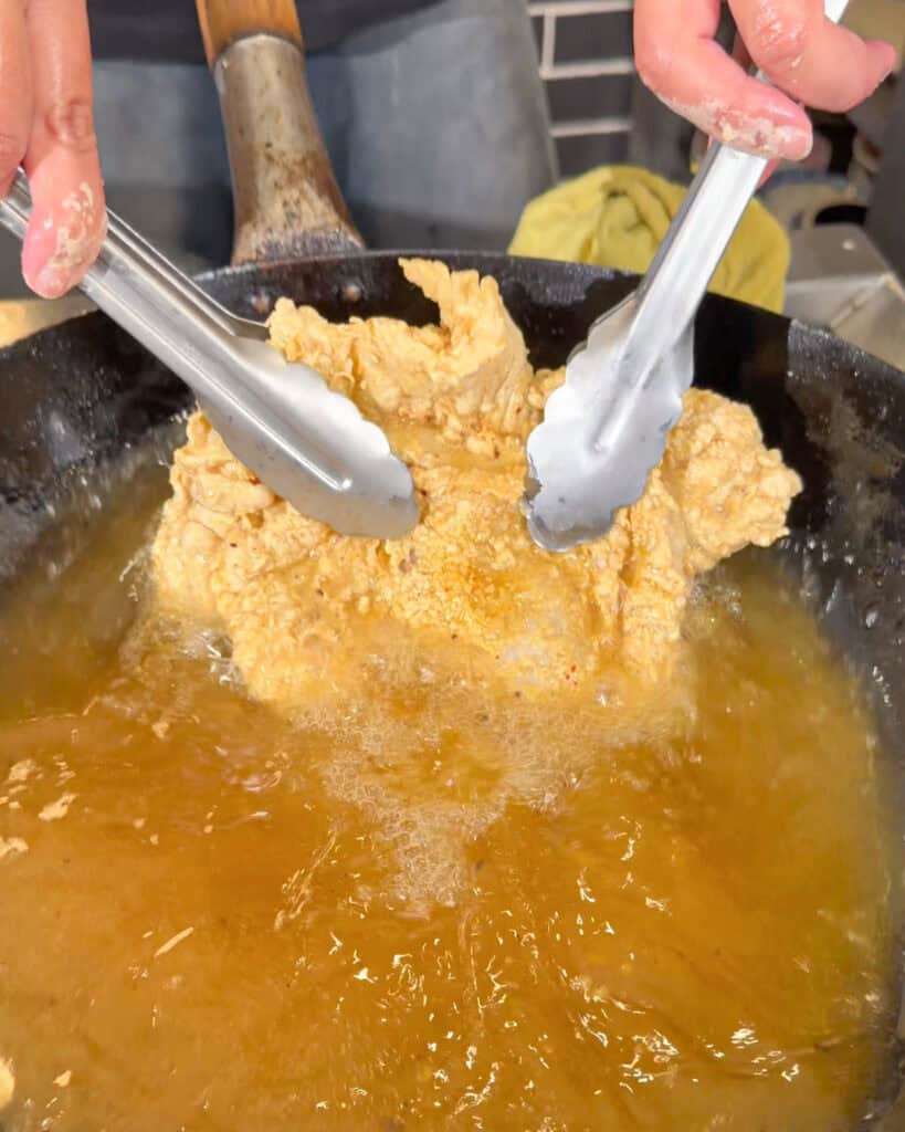 Chicken fully coated in dry flour batter before frying for crispy chicken chop.