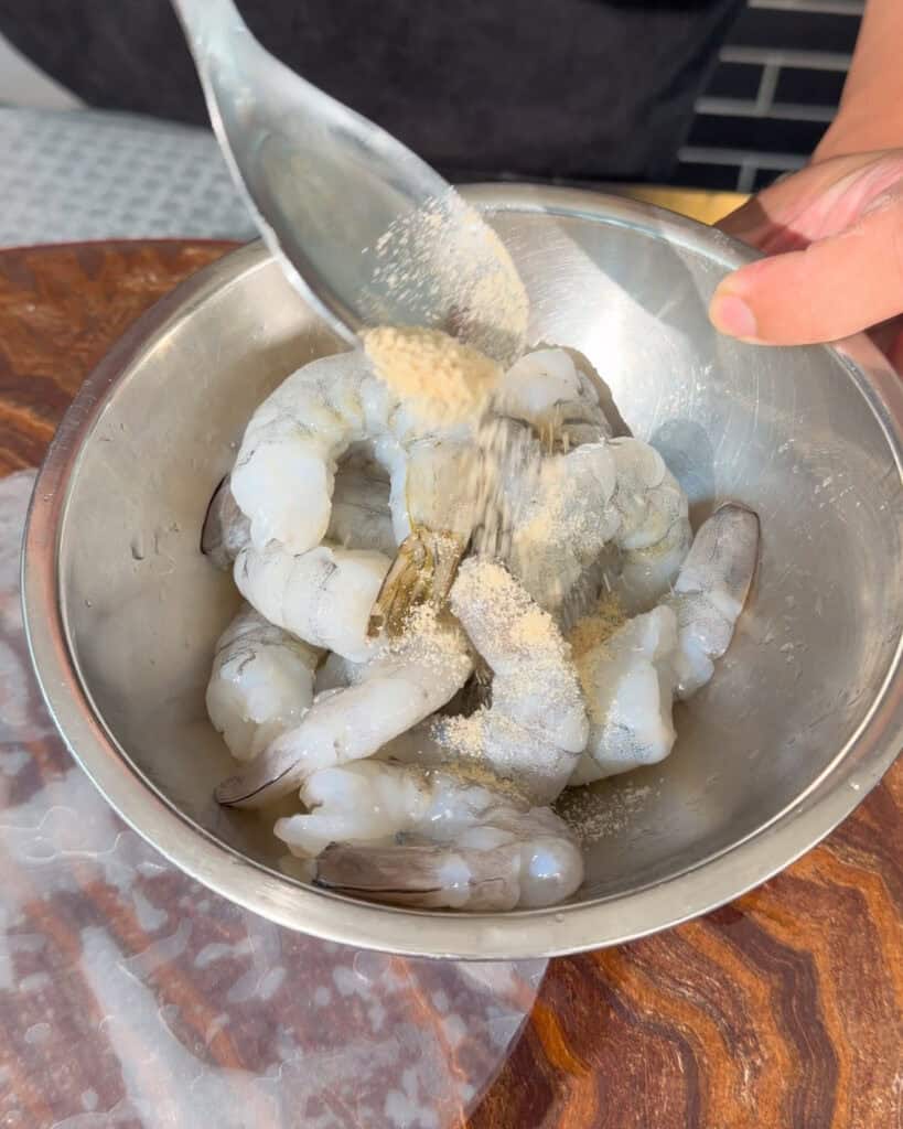 Raw prawns in a bowl with powder seasoning added