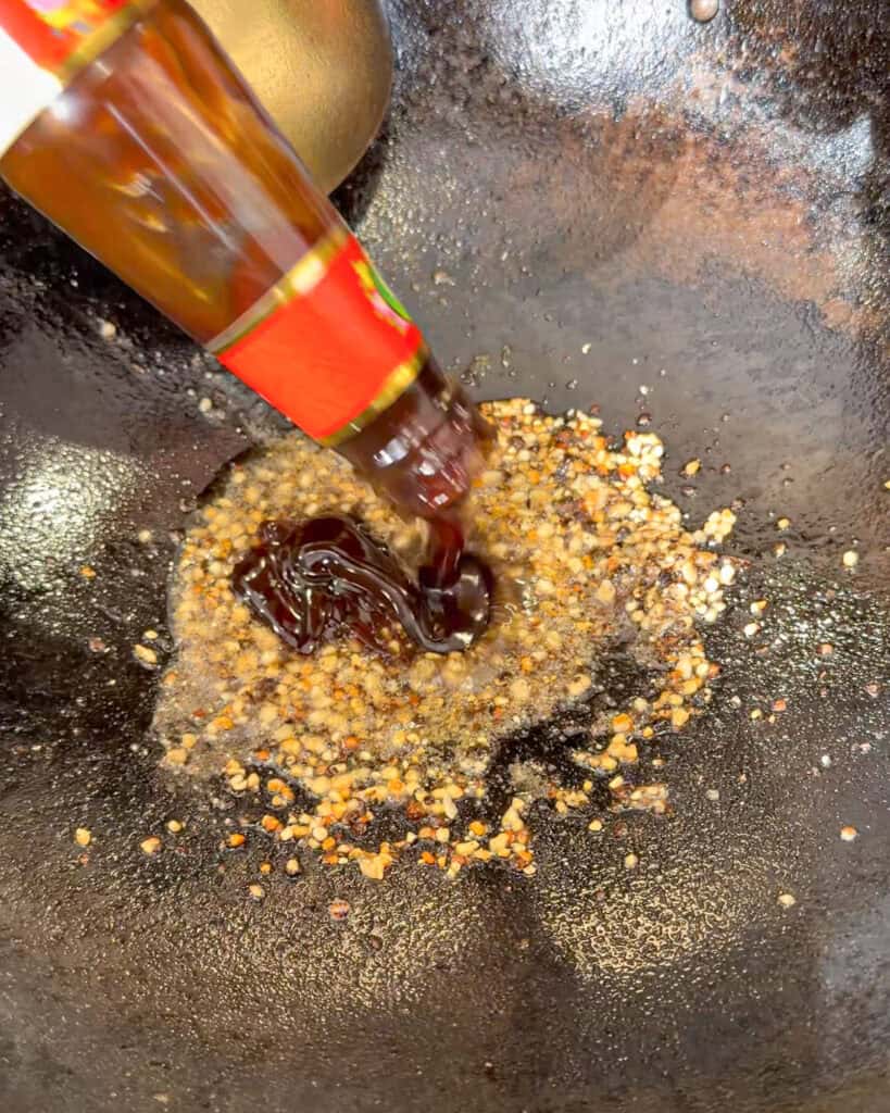 Sauce ingredients being added to a wok during chicken sauce preparation