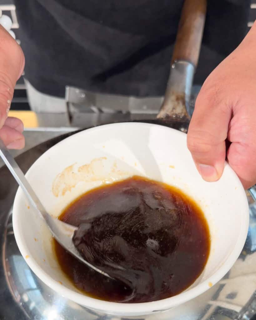 Stirring dark sauce in a white bowl