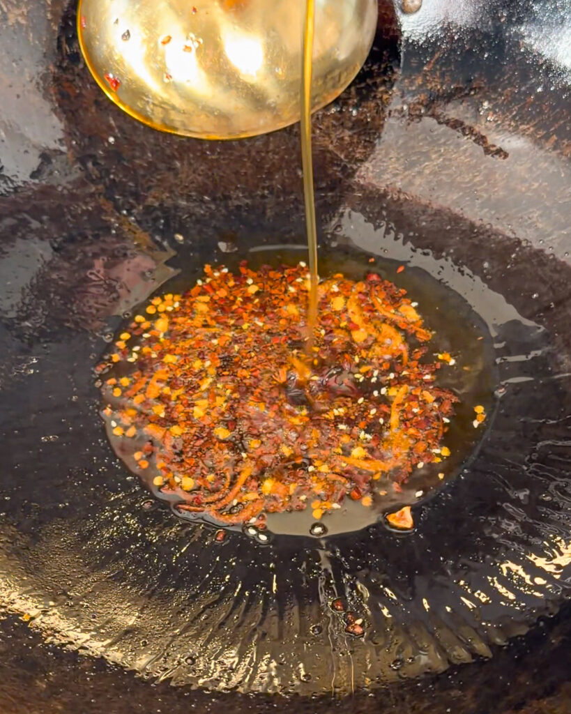 Chilli flakes and oil in a wok for hot honey lemon sauce