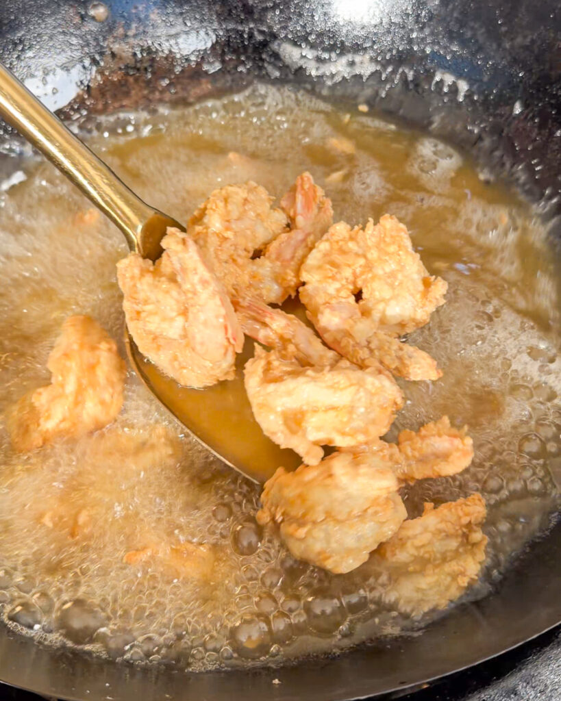 Golden fried king prawns lifted from bubbling oil